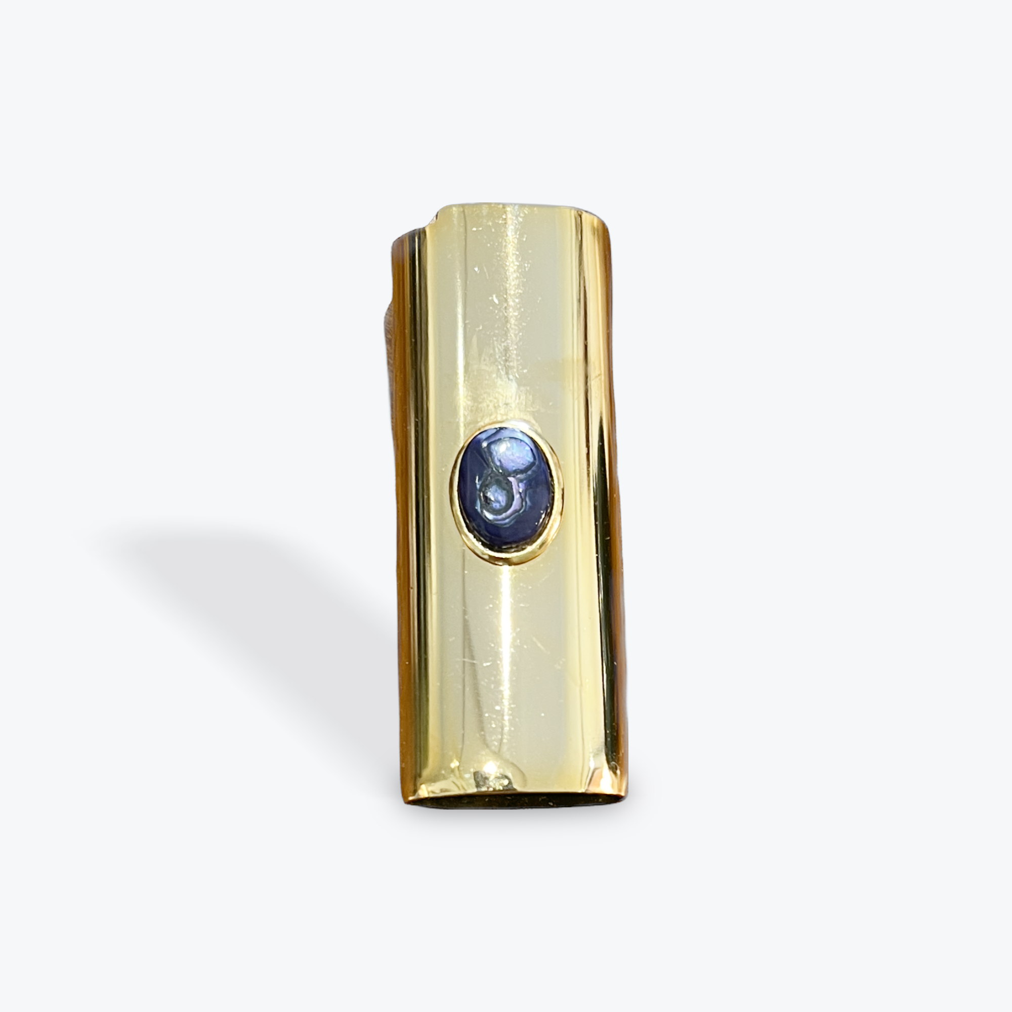 Gold lighter case with a bluish purple abalone stone on a white background