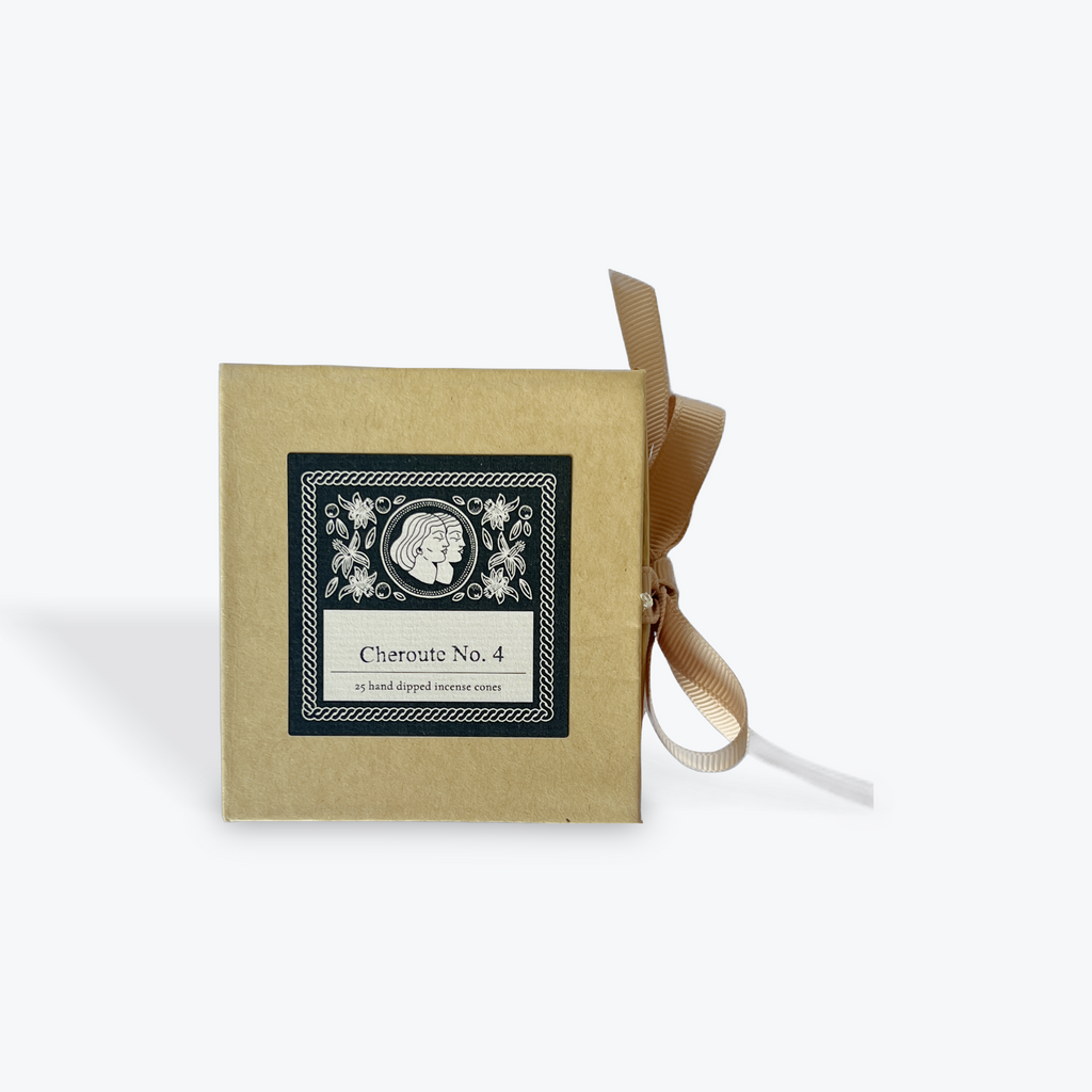 A square kraft paper box with a black and white decorative label reading 'Cheroute No. 4' and a tan ribbon tied in a bow, photographed on a light gray background.