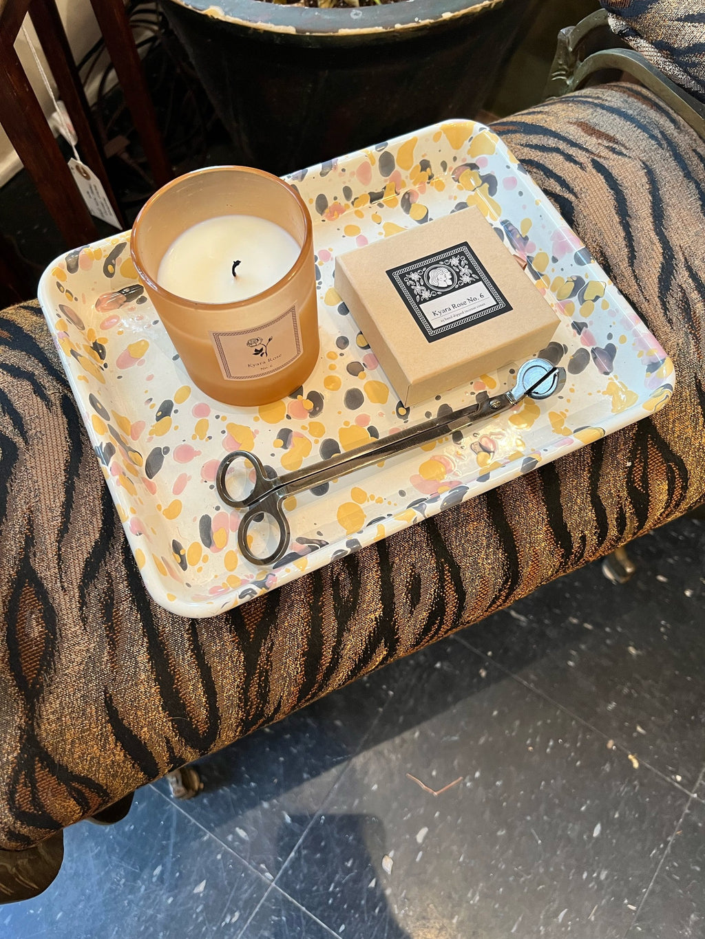 Candle, incense box, and wick trimmers on a decorative tray with a tiger-patterned stool.
