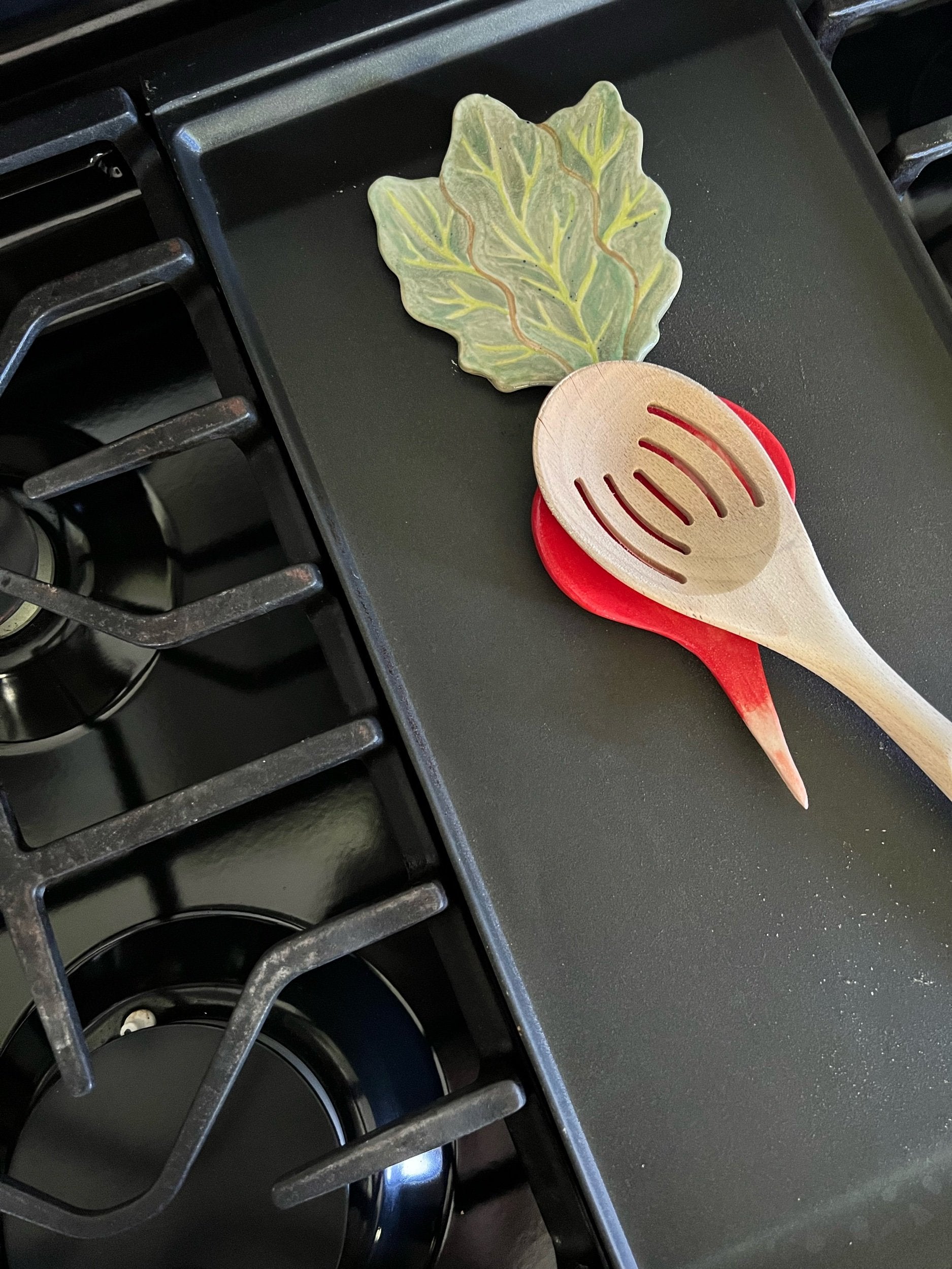 Wooden spoon on  radish-shaped spoon rest on a stovetop