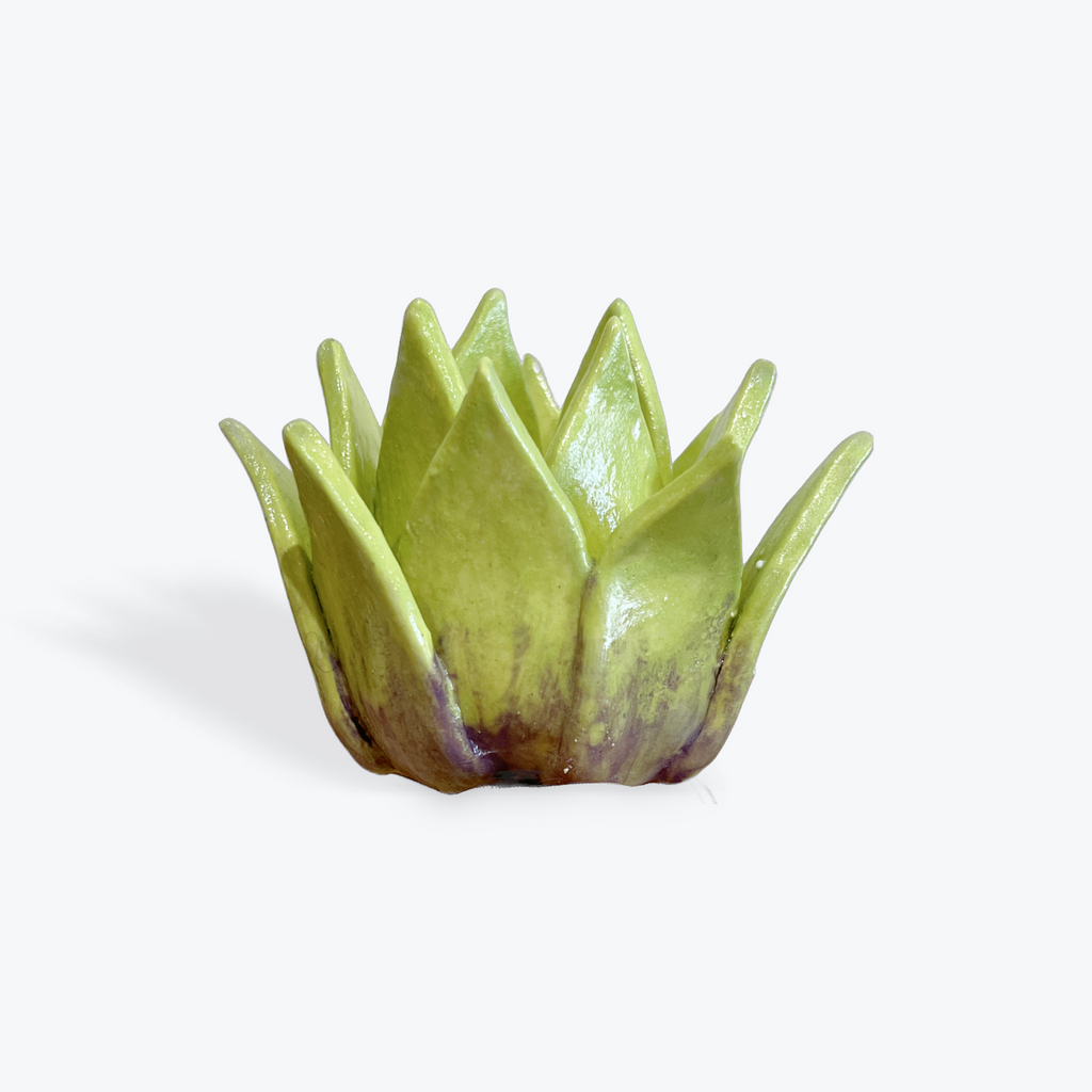 Green ceramic artichoke heart with subtle purple effect on the bottom on a white background
