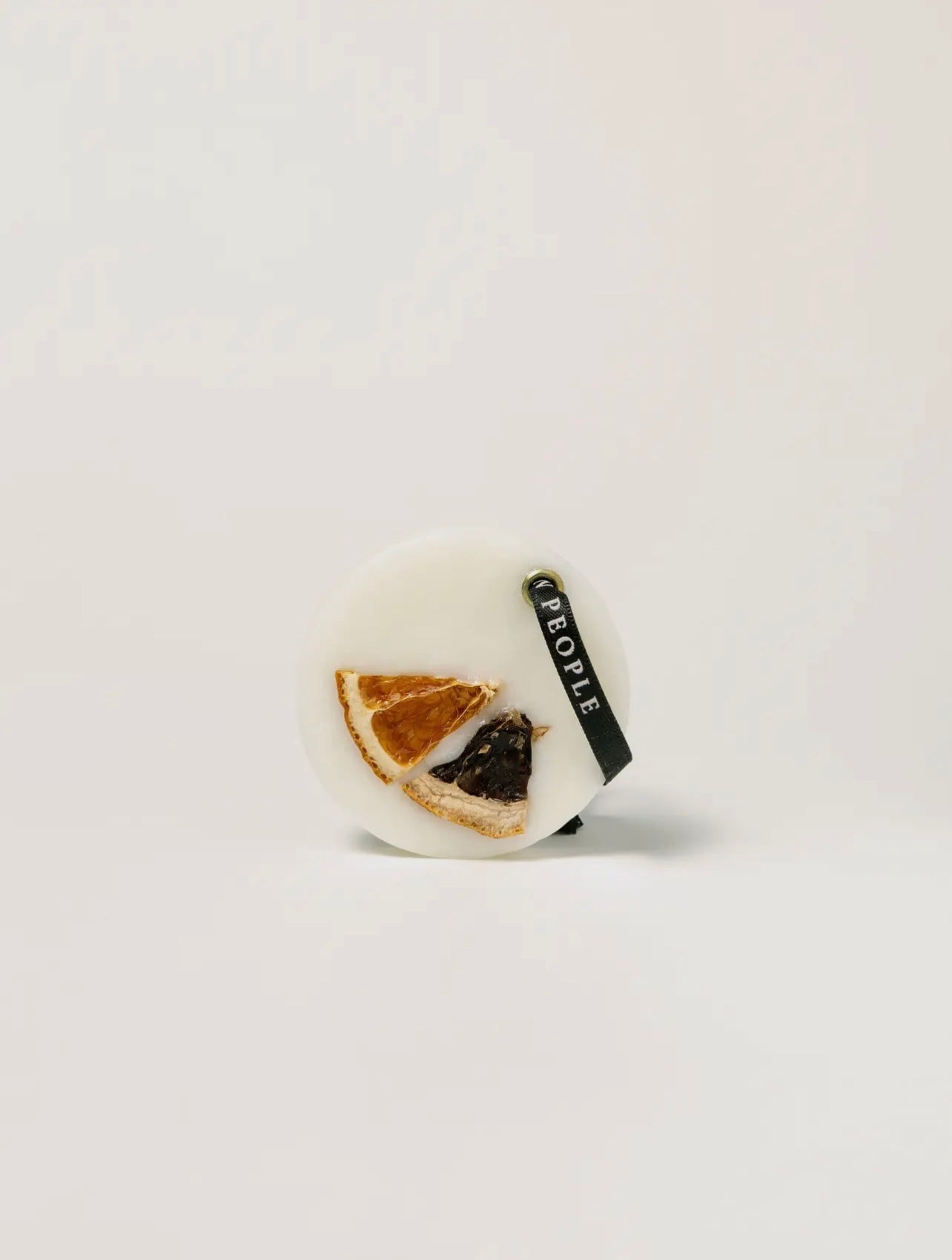 Round wax bar with dried orange slices on a light gray background