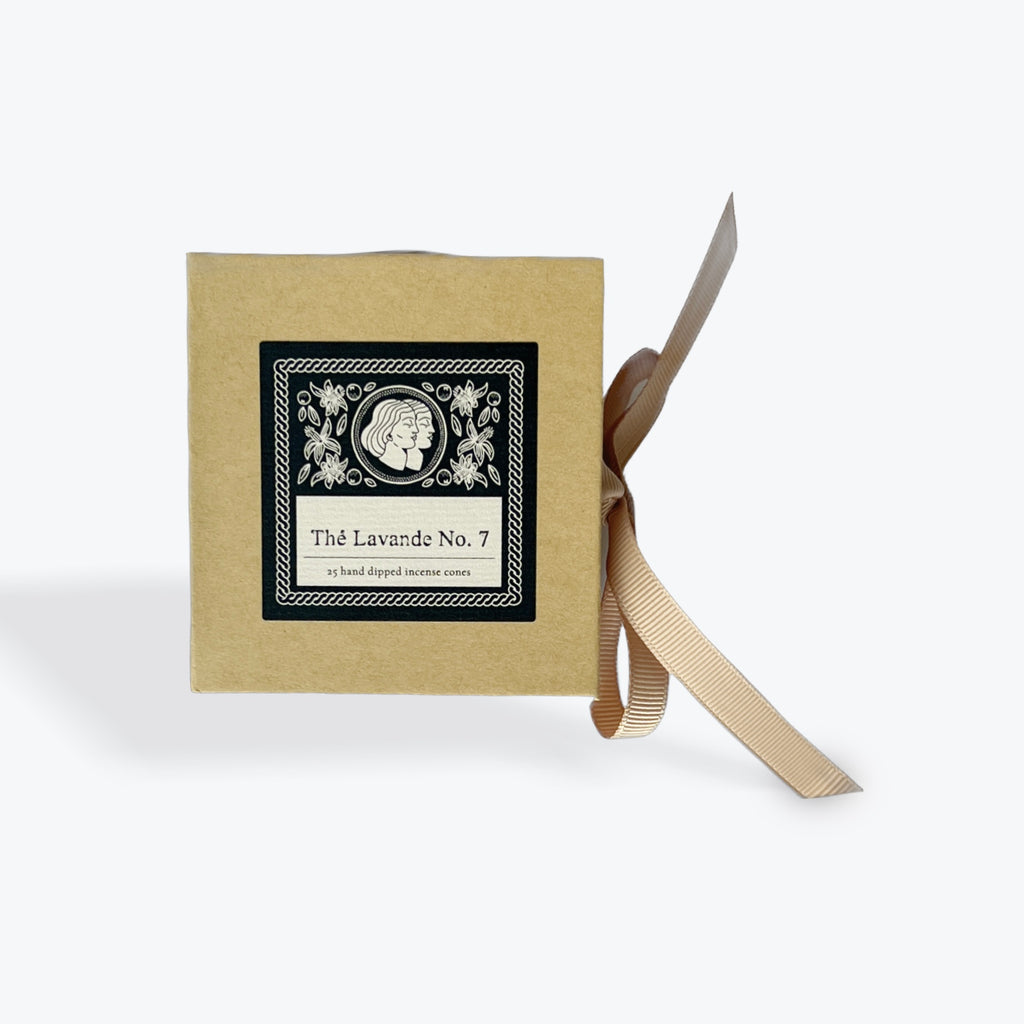 A square kraft paper box with a black and white decorative label reading 'Thé Lavande No. 7' and a beige ribbon tied around it, shown on a light gray background.