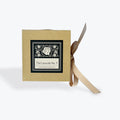 A square kraft paper box with a black and white decorative label reading 'Thé Lavande No. 7' and a beige ribbon tied around it, shown on a light gray background.