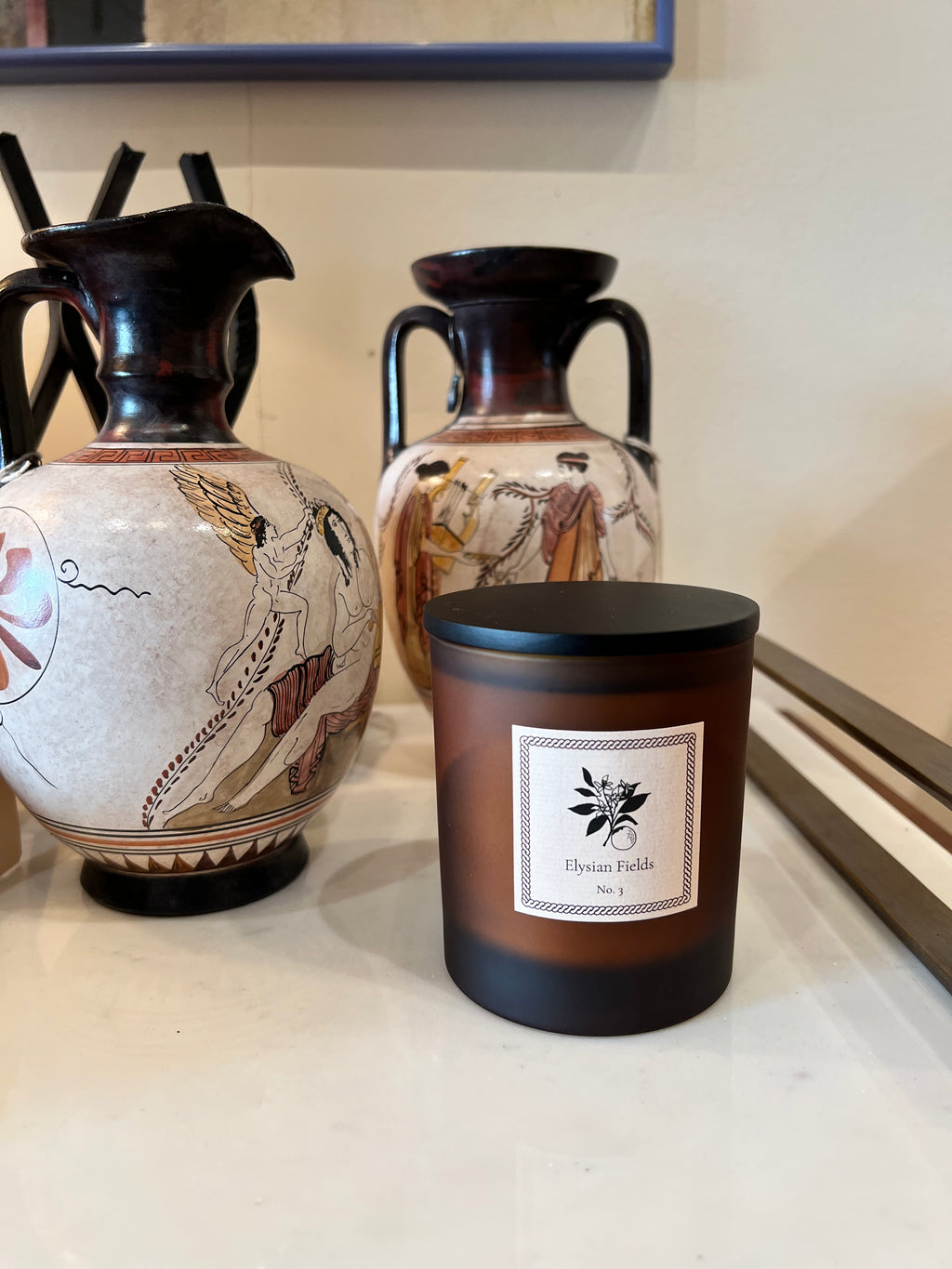 Decorative vases with intricate designs and a amber candle vessel with black lid on a white surface