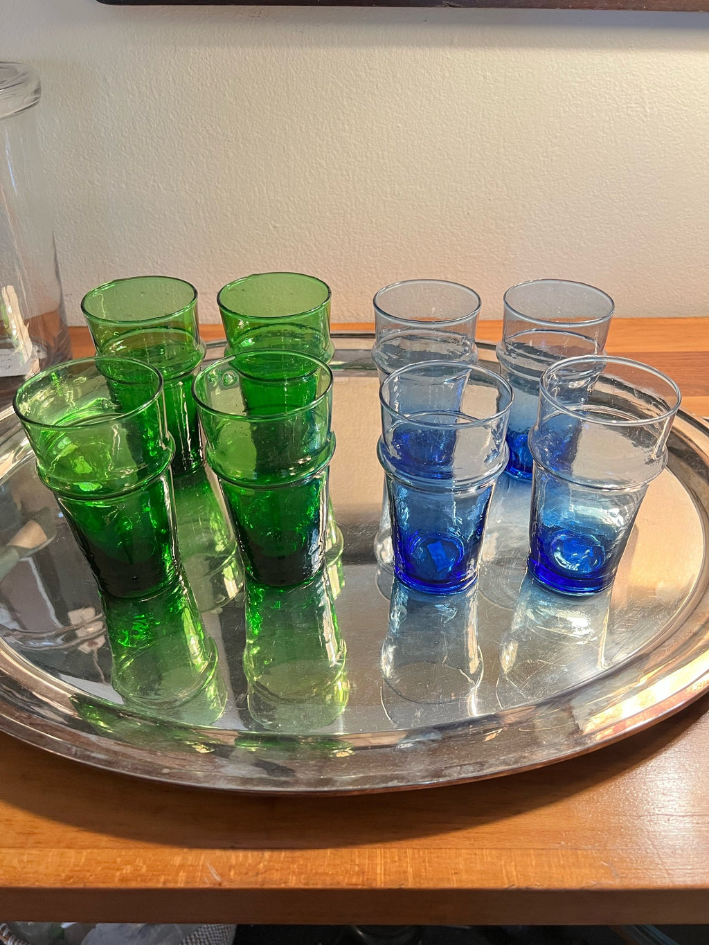 Set of green and blue drinking glasses on a silver tray.