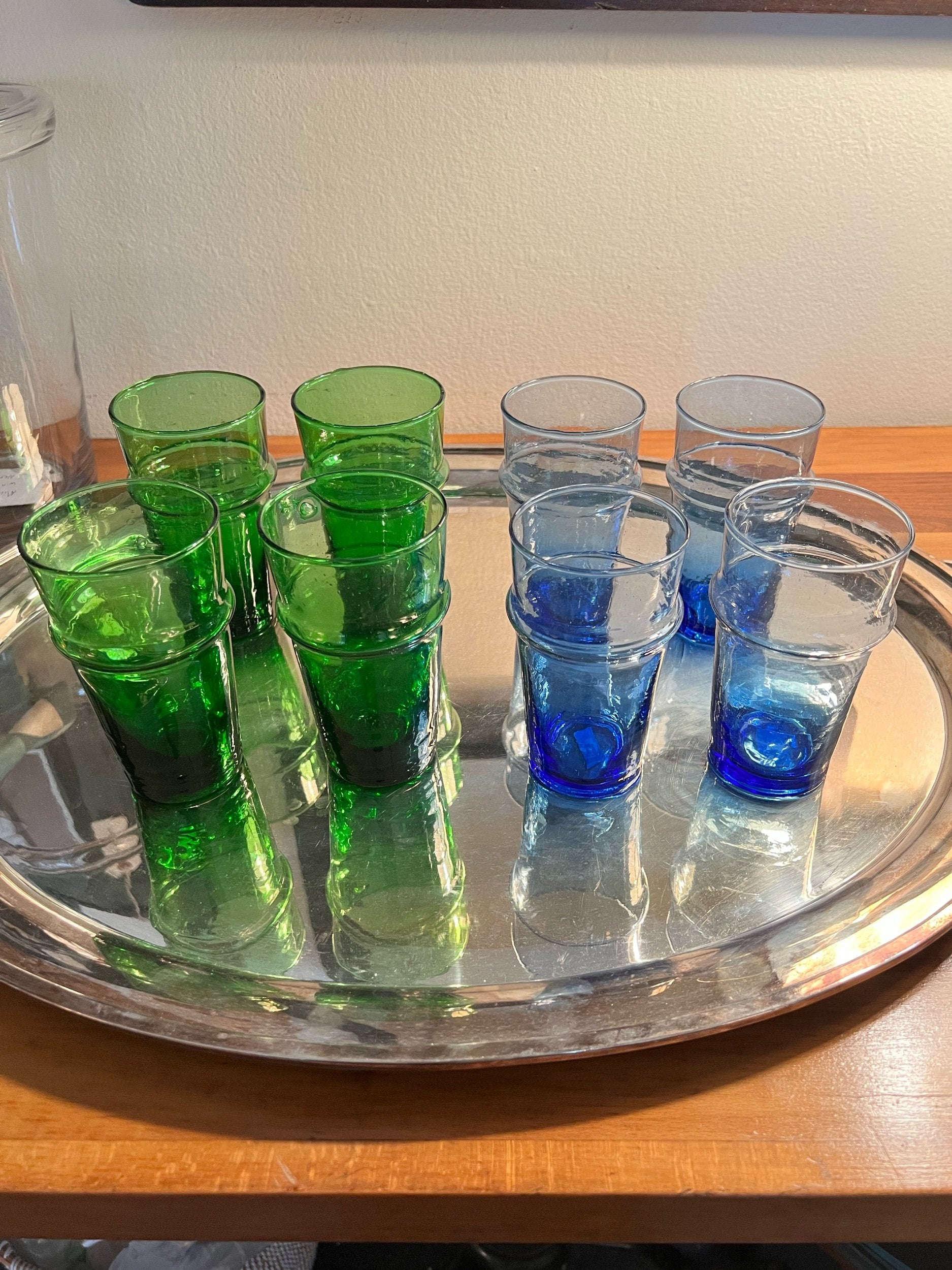 Set of green and blue drinking glasses on a silver tray.