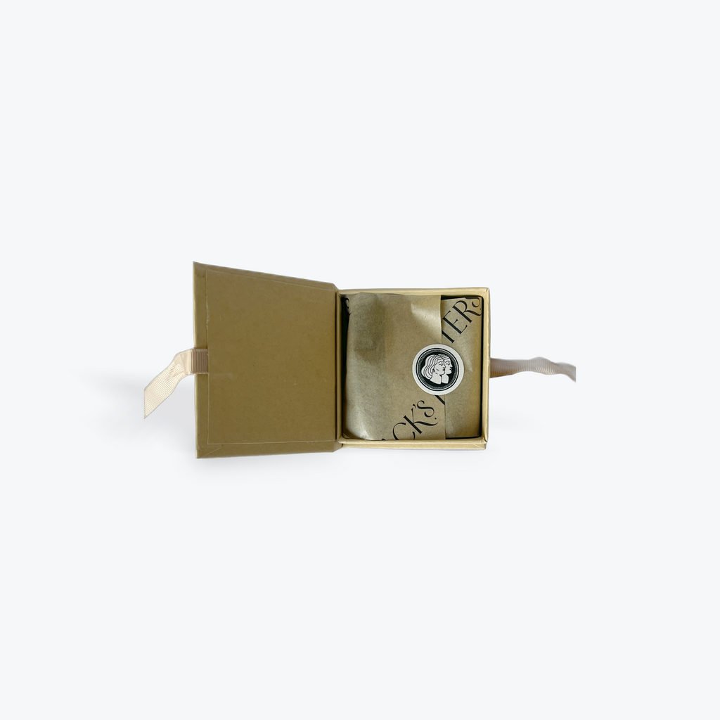 An open kraft box used for incense with a round label with two faces in profile on a white background. 