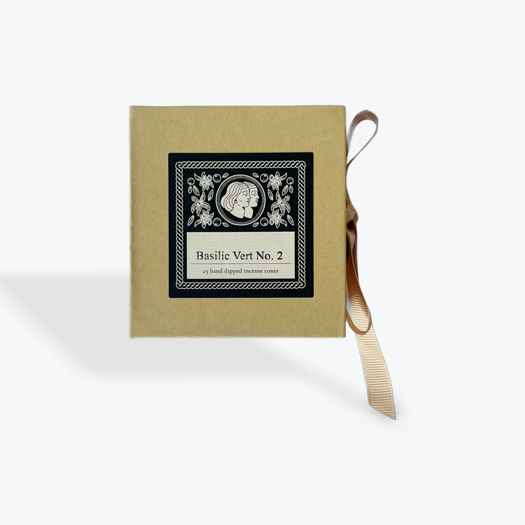 A square kraft paper box with a black and white decorative label reading 'Basilic Vert No. 2' and a beige ribbon tied to the side, shown on a light gray background.