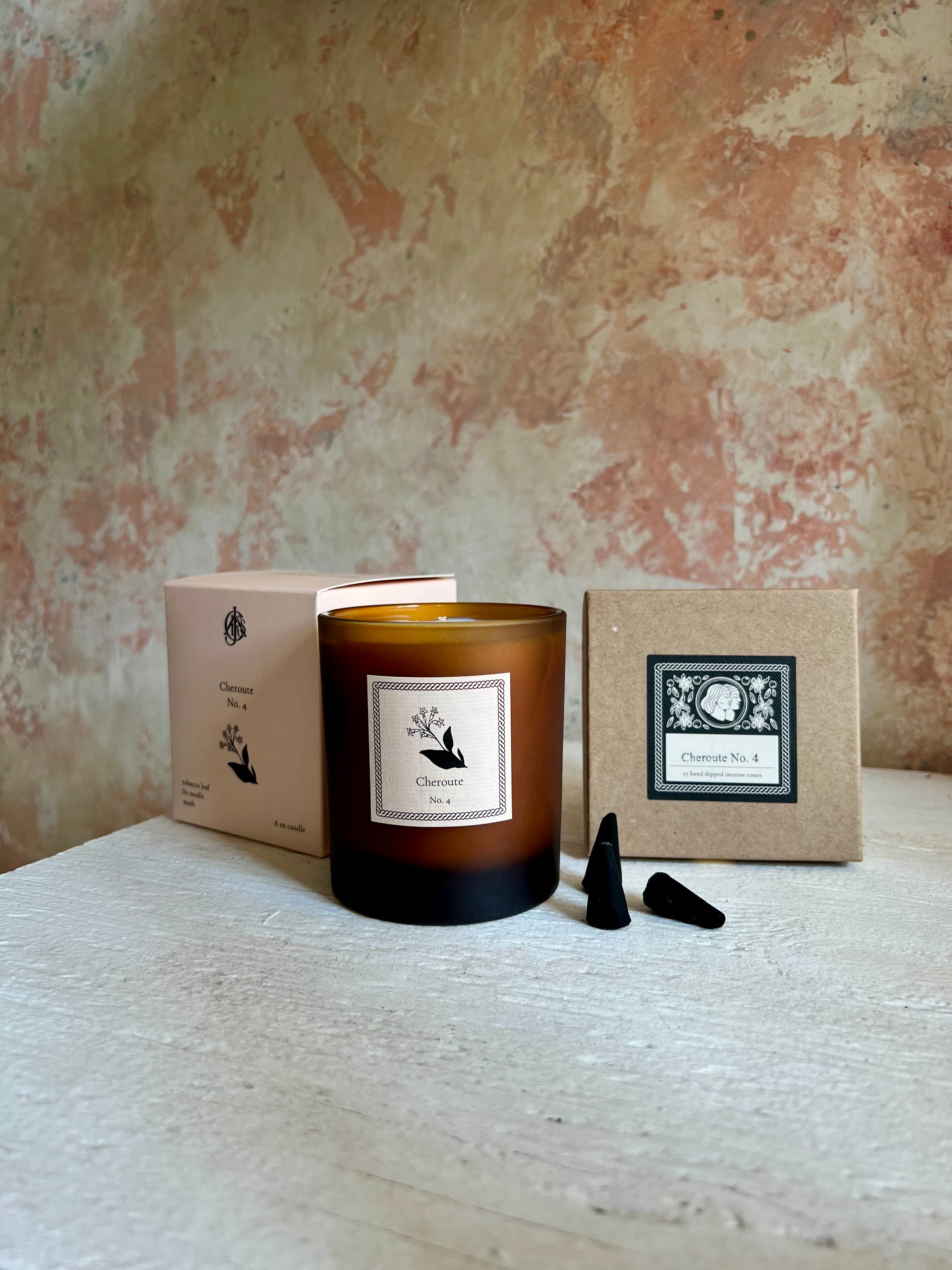 Candle with packaging and incense cones on a textured surface