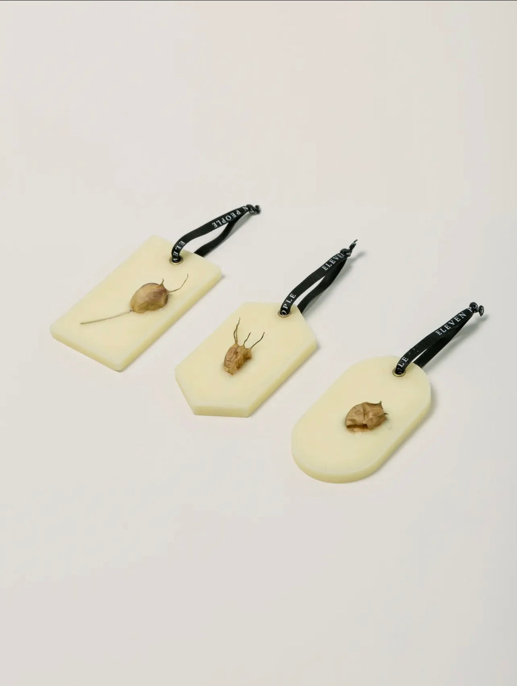 Three white wax bars with pressed leaves  on a light gray background