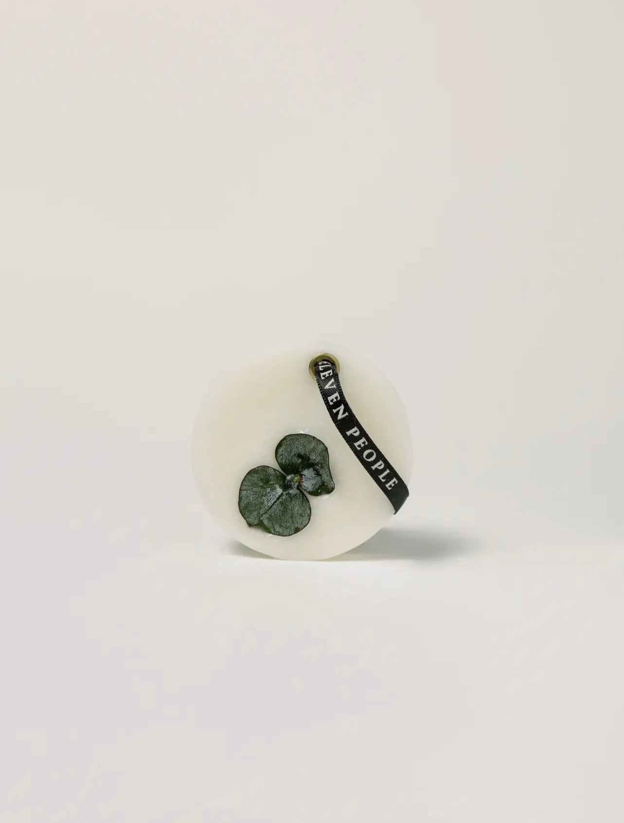 Round wax bar with dried flowers on a light gray background