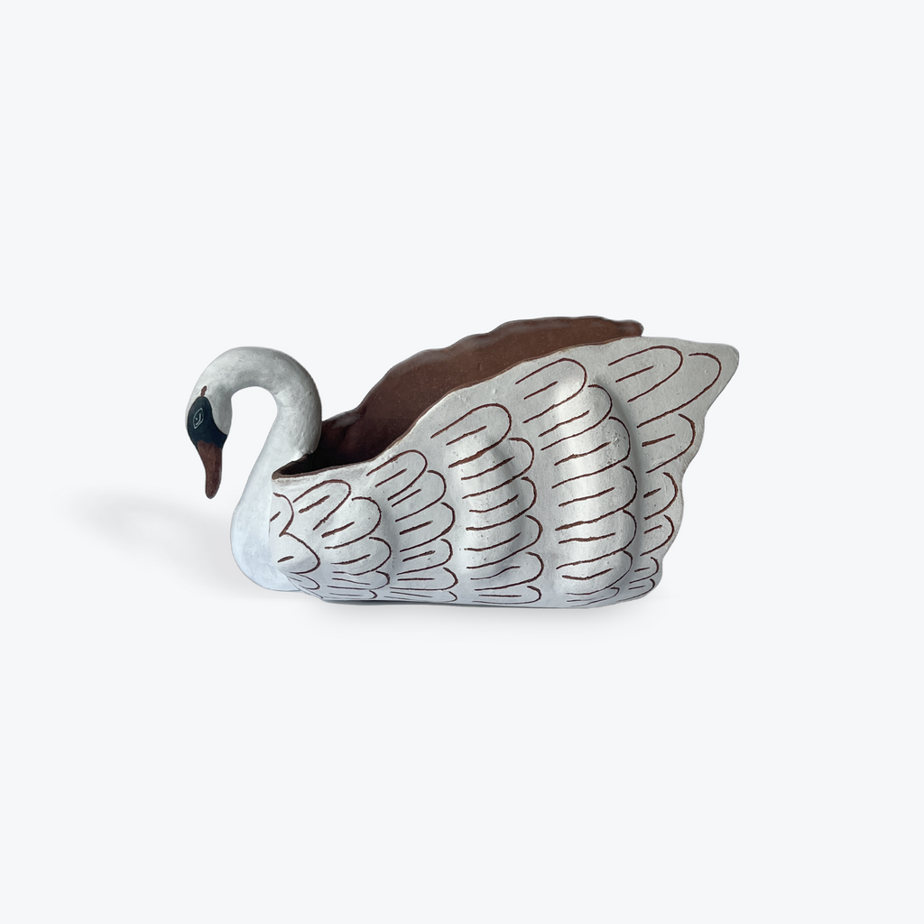 A decorative ceramic swan figure on a white background. 