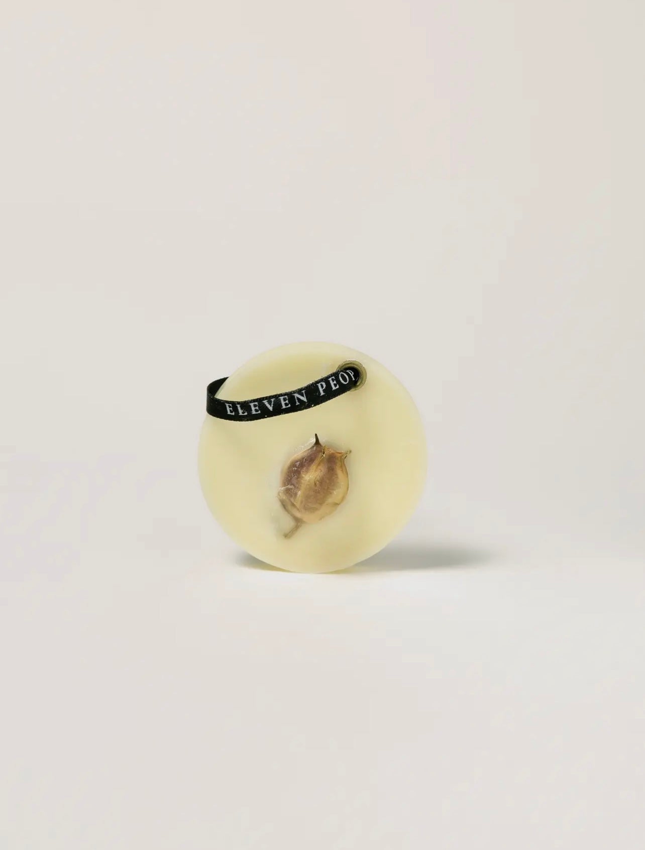 Round wax bar with dried flowers on a light gray background