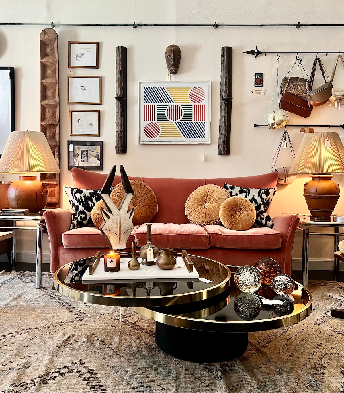 Vignette at Afternoons shop with a pink sofa, round coffee table, and decorative wall art.