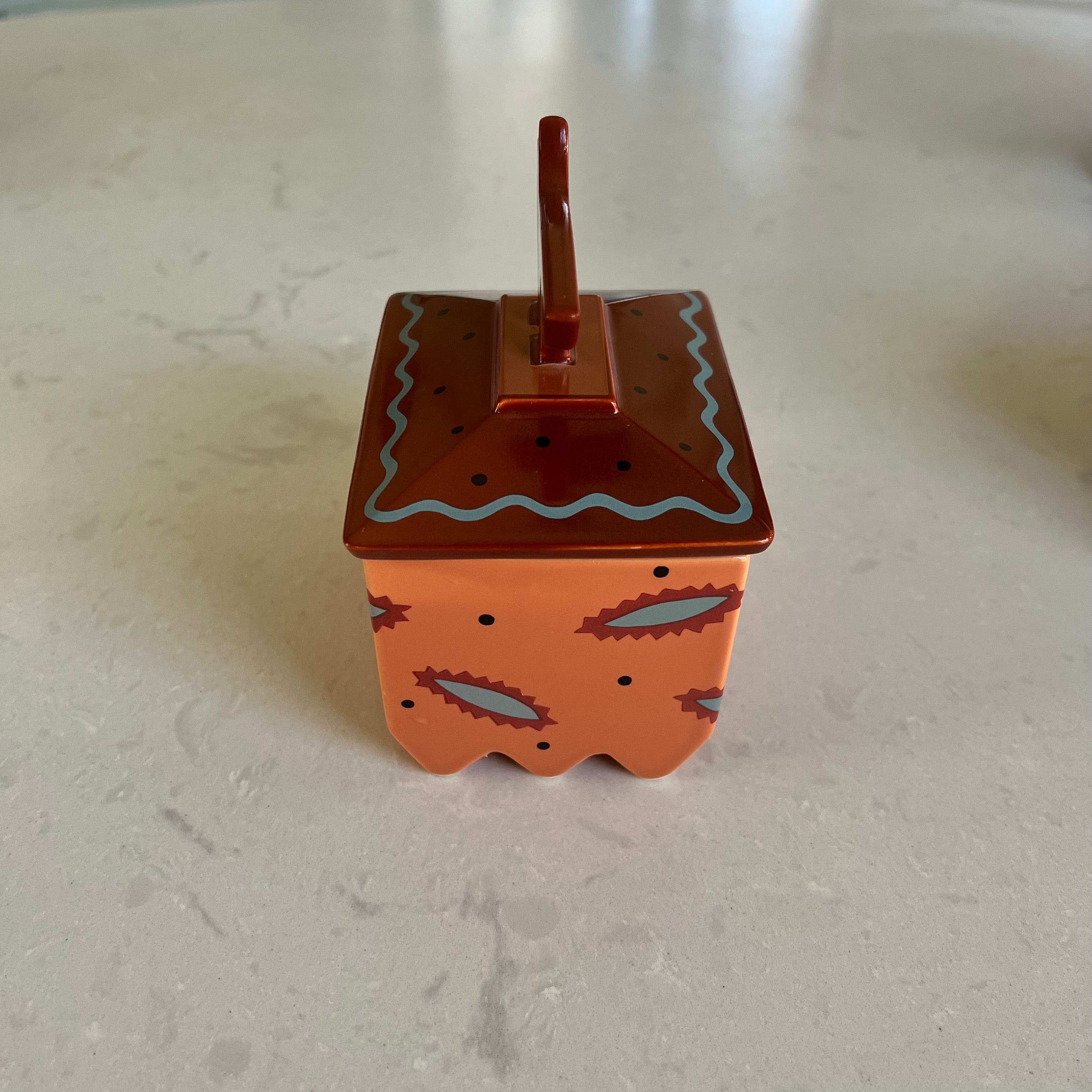 The side of a small decorative box with a lid on a light gray surface