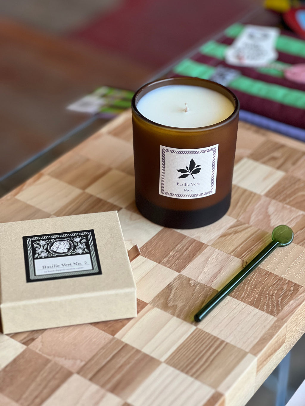 Candle with a label and box of incense on a checkered cutting board