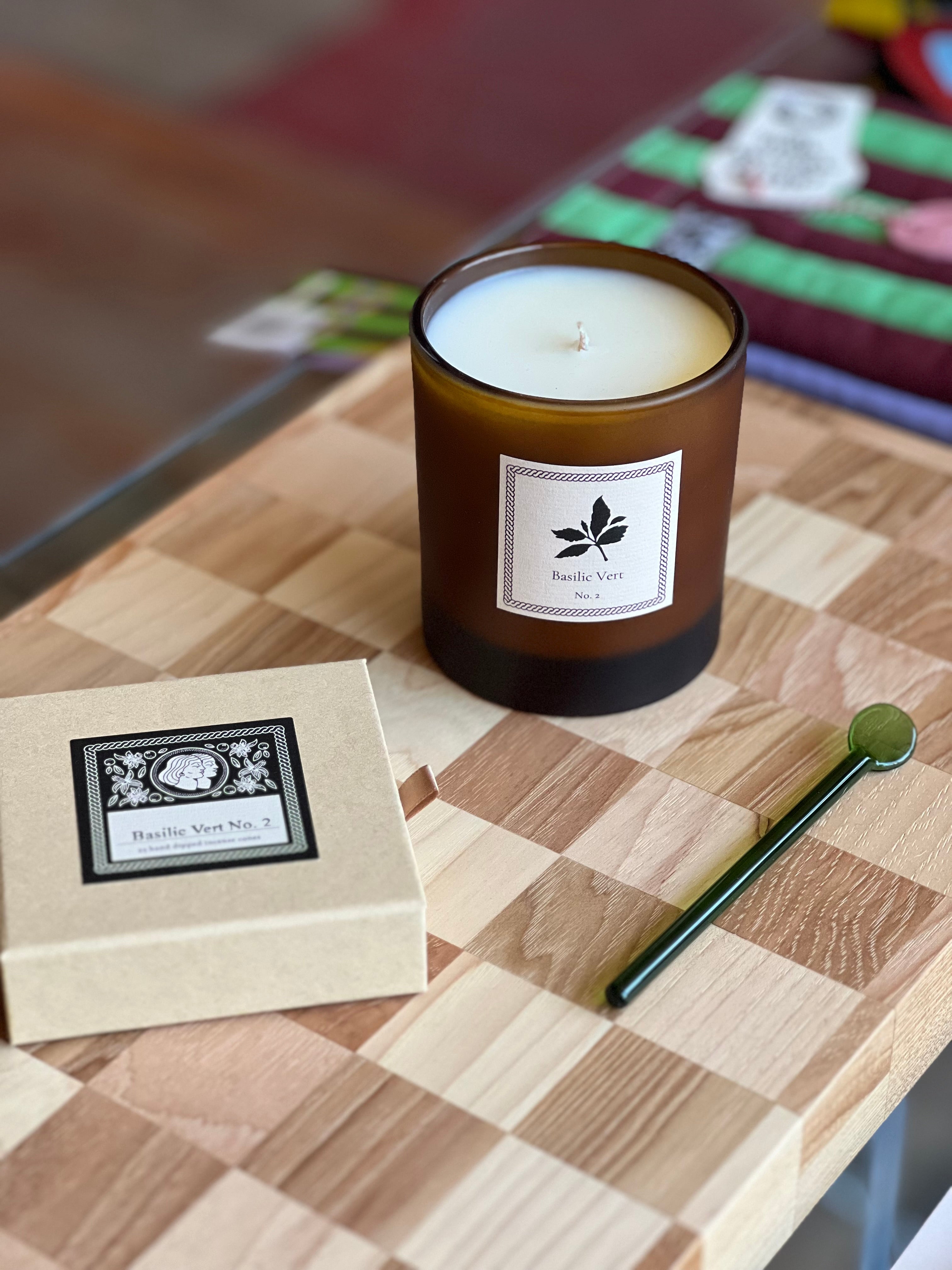 Candle with a label and box of incense on a checkered cutting board