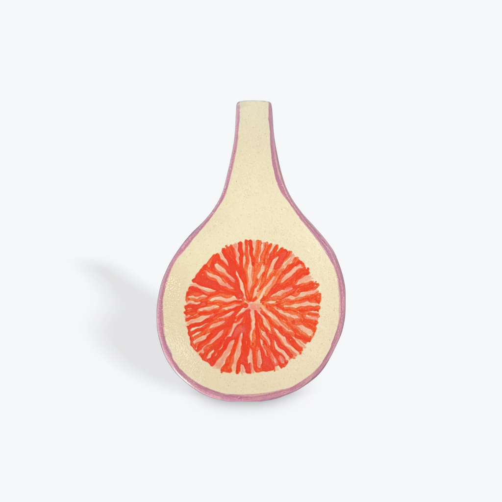 Ceramic spoon rest made to look like a sliced fig on a white background