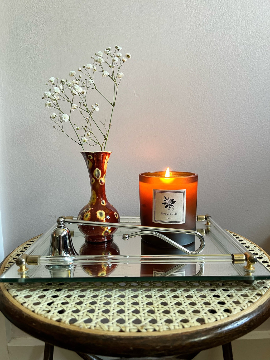 Candle, snuffer and vase on a decorative table with a plain background