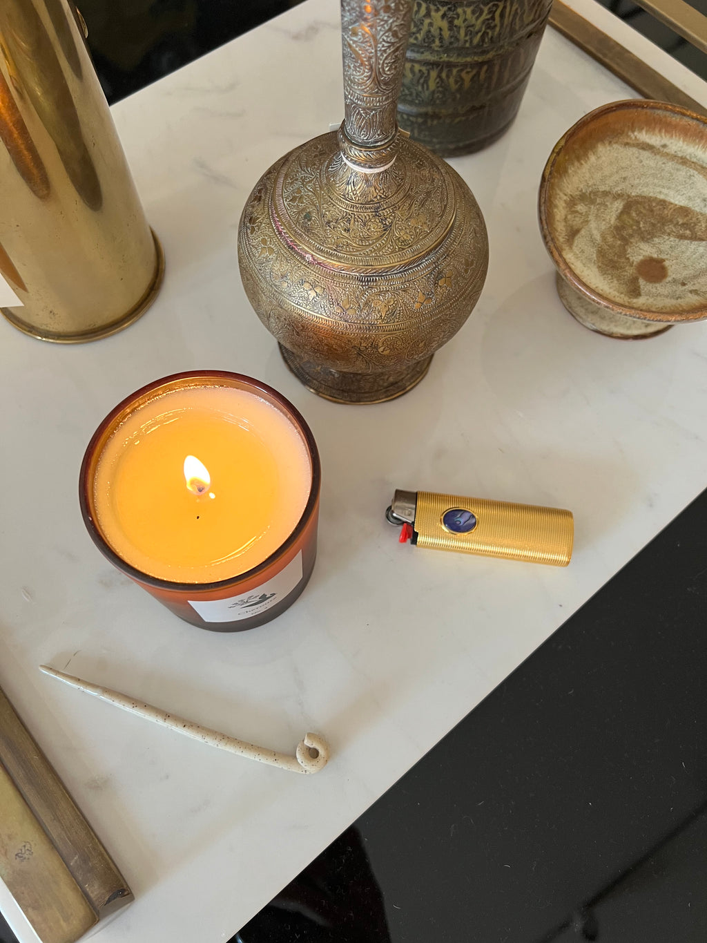 Candle, lighter, and decorative items on a white surface