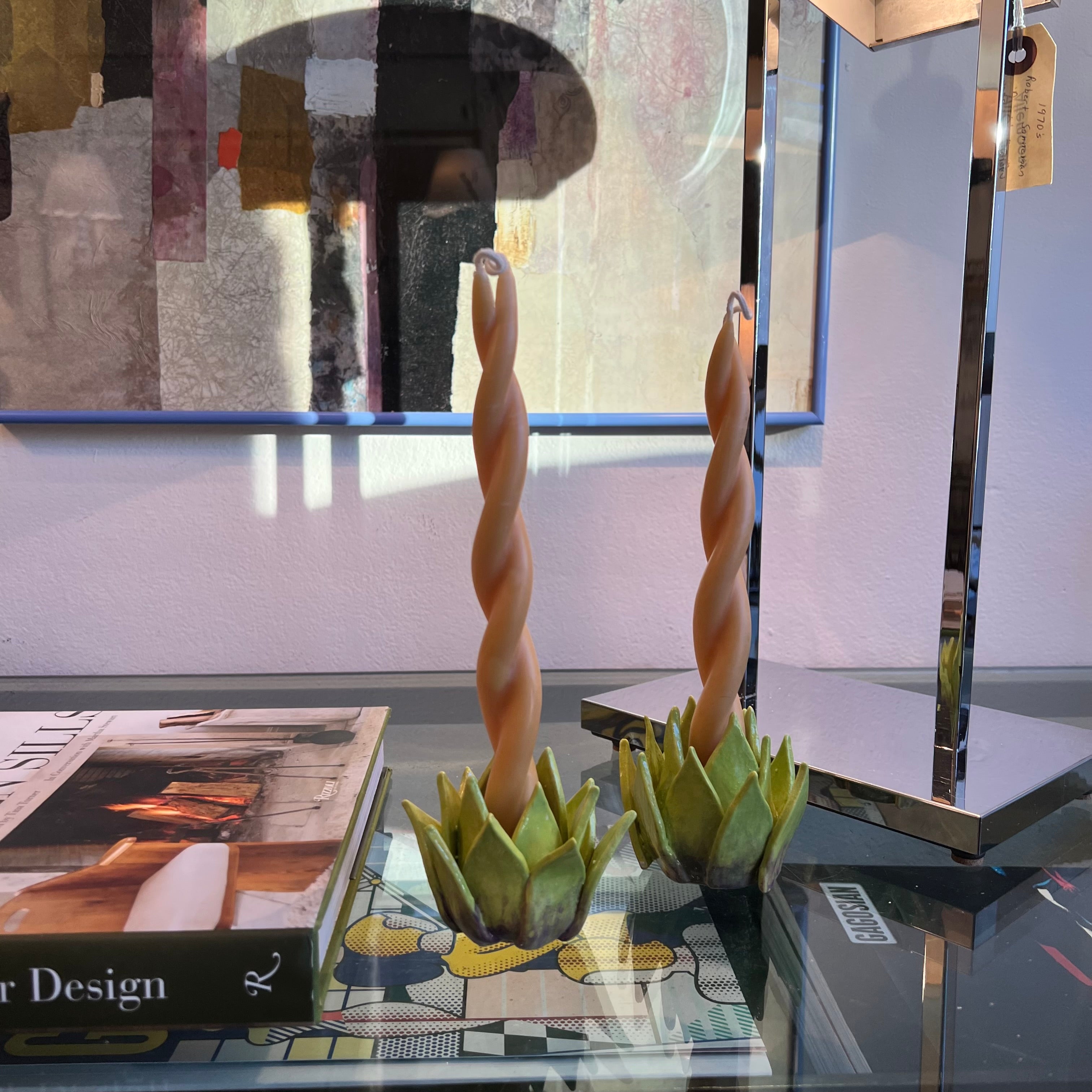 Two ceramic green artichoke hearts that function as taper candle holders with an abstract background 