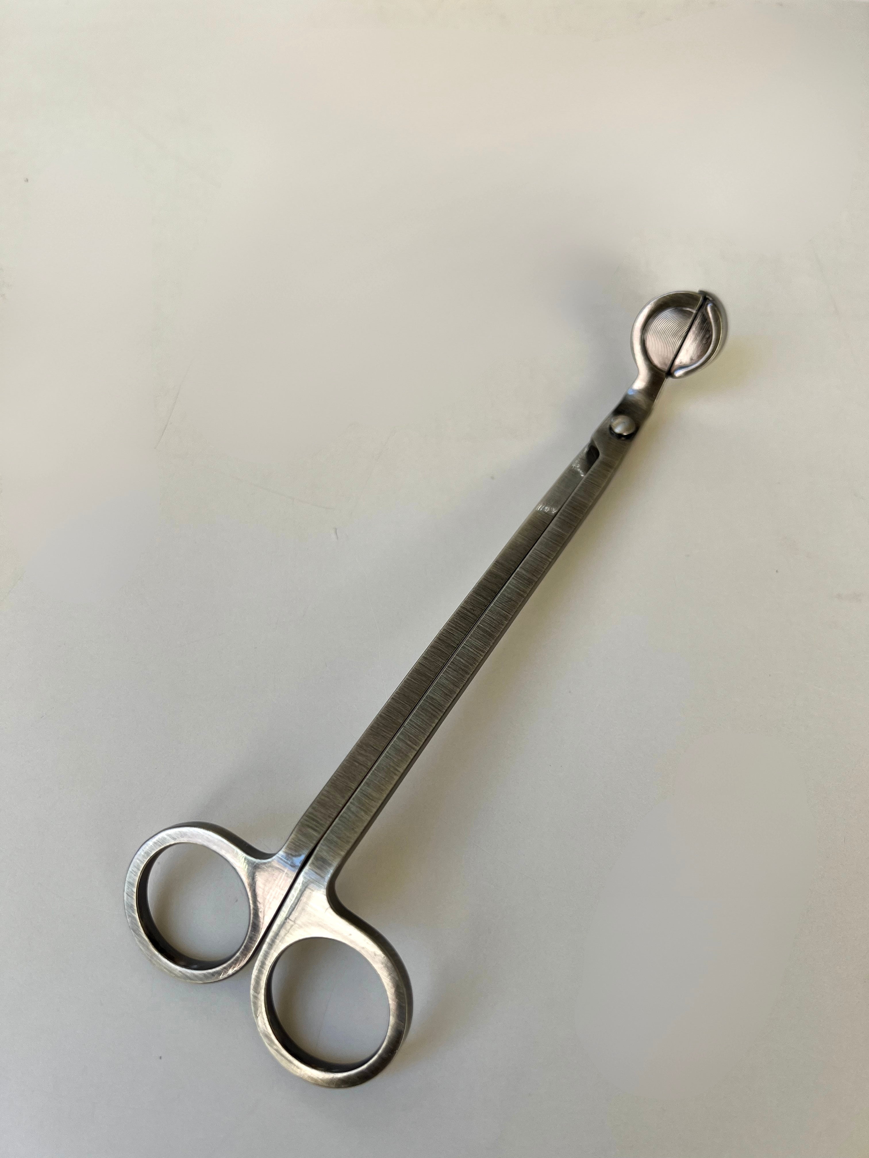 Antique brass wick trimmers on a light cream background 