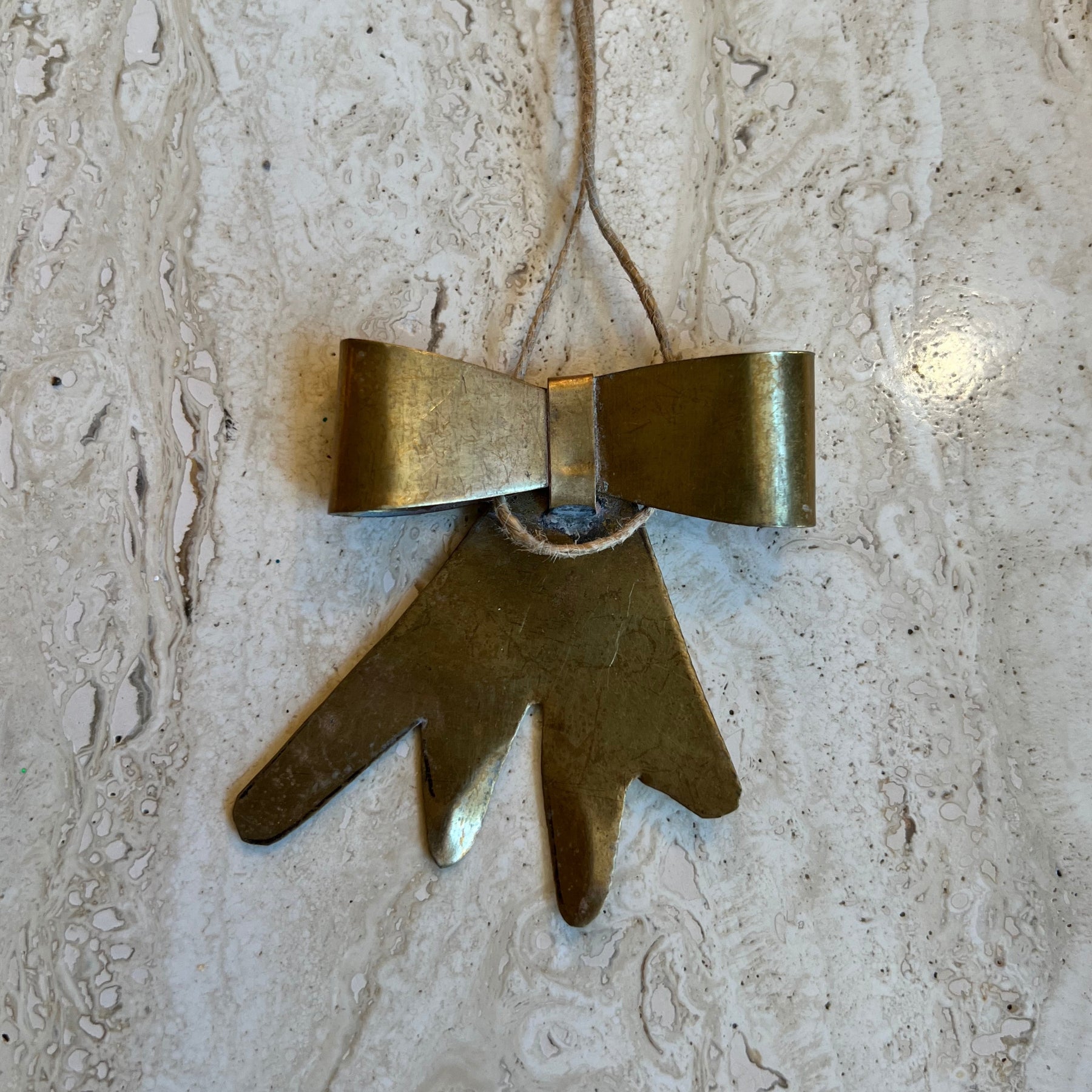 Brass bow ornament on a beige travertine surface