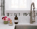 Kitchen sink area with soap dispenser, flowers, and a faucet.