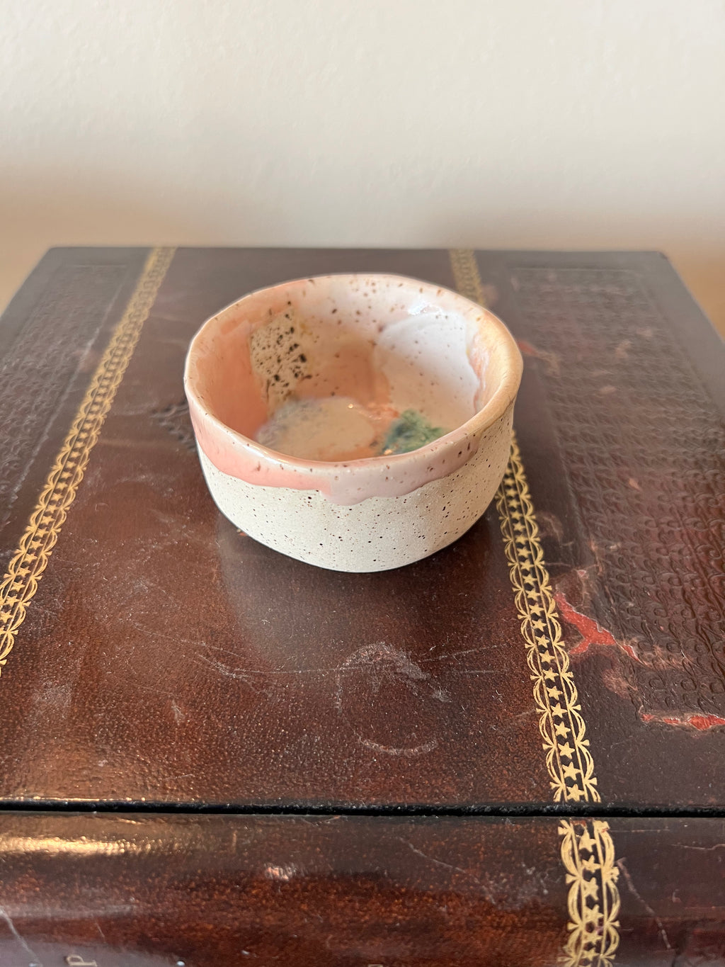 Small ceramic bowl on a textured surface with decorative gold accents