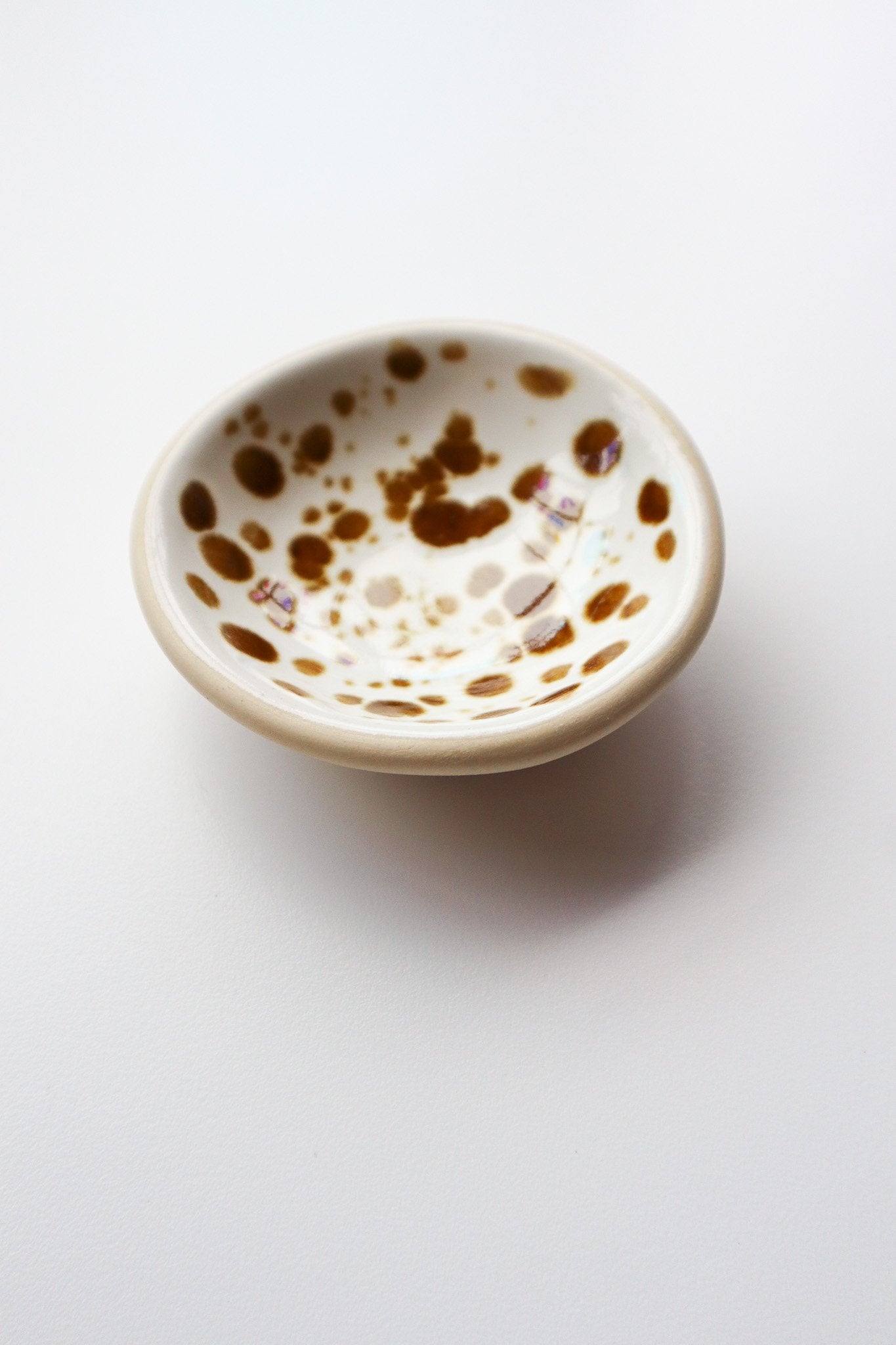 Small ceramic bowl with brown speckles on a white background