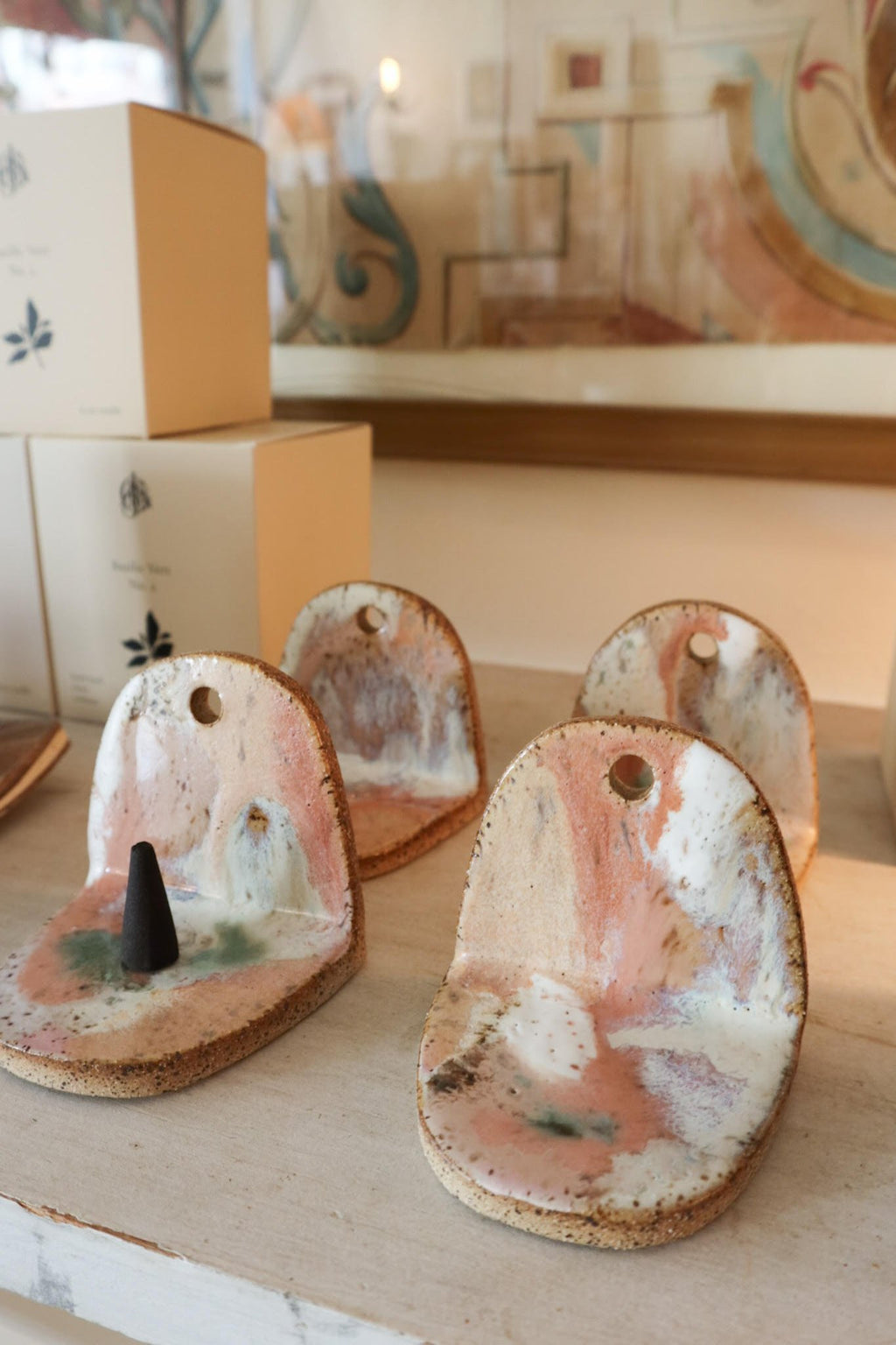 Set of ceramic incense holders with a black incense cone on a wooden surface.