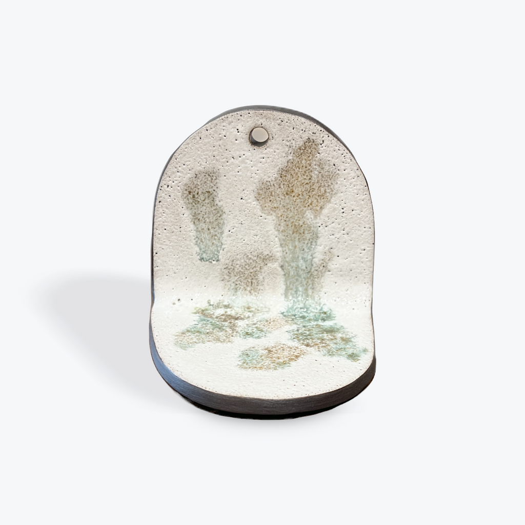 Decorative ceramic piece with light green splotches on a white background