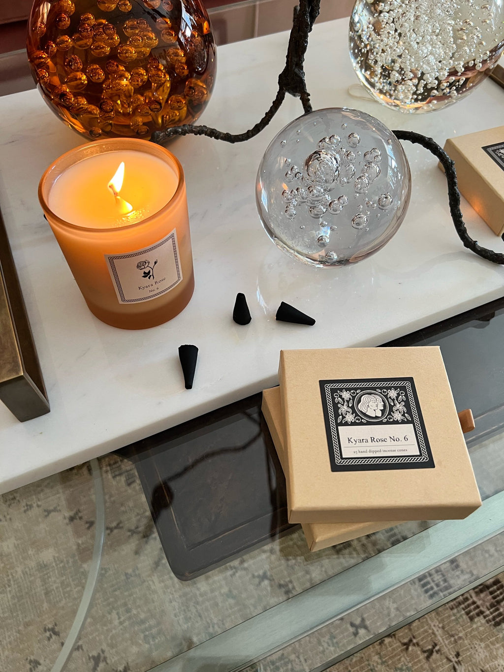 Candle, incense cones, and a box on a surface with a blurred background