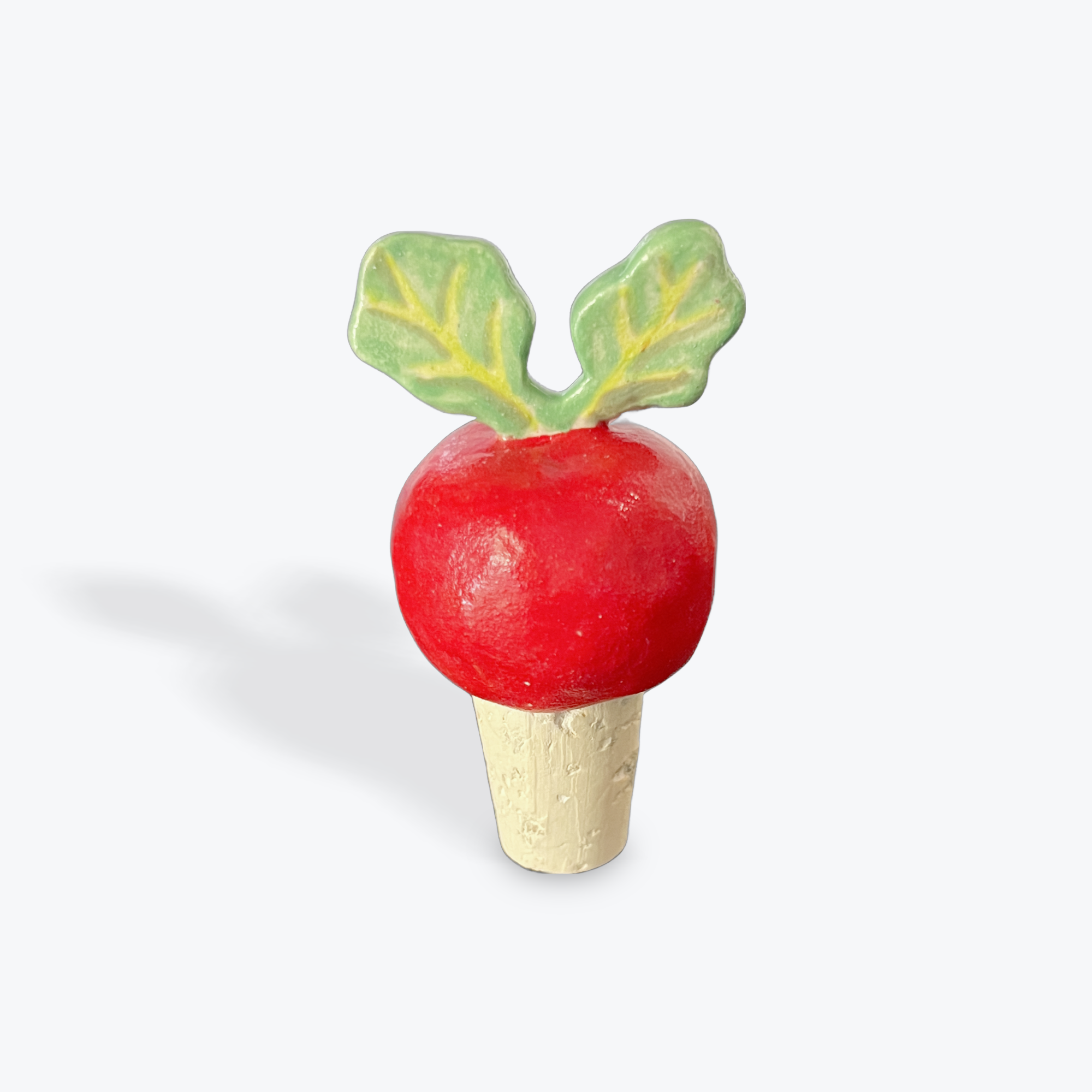 Red radish-shaped bottle stopper with green leaves on a white background
