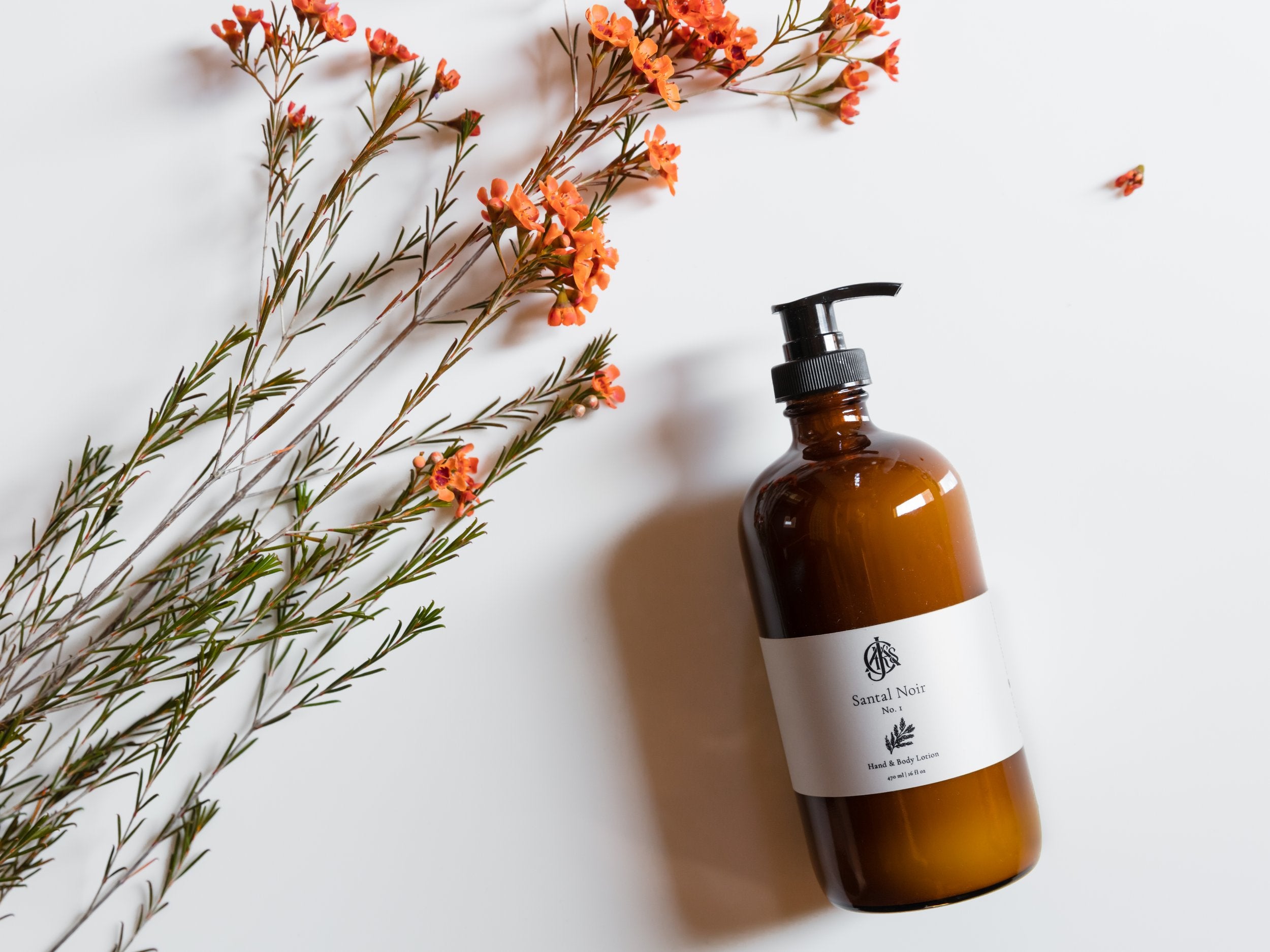 Brown bottle with pump and label on a white background with orange flowers