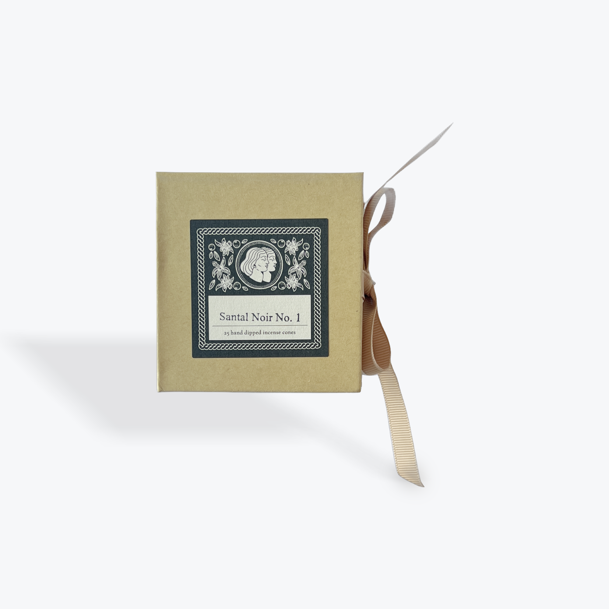 A square kraft paper box with a label reading 'Santal Noir No. 1' and a beige ribbon tied around it, photographed on a clean white background.