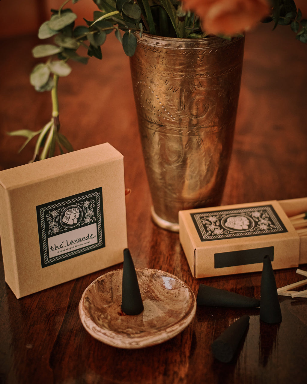 Incense cones on a dish with decorative boxes and a vase in the background
