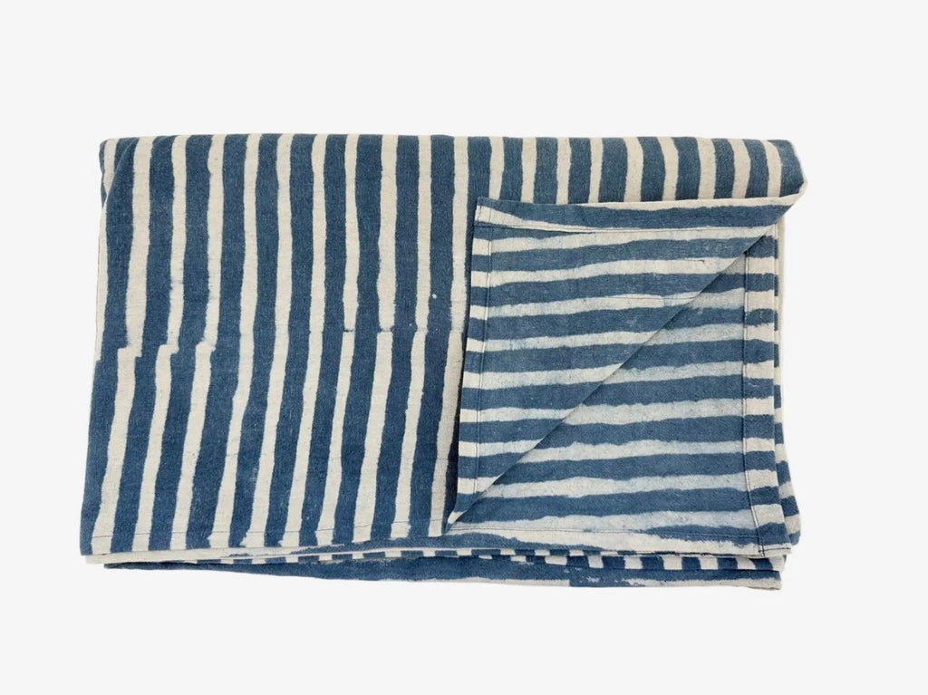 A blue and white stripe throw folded on a white background. 
