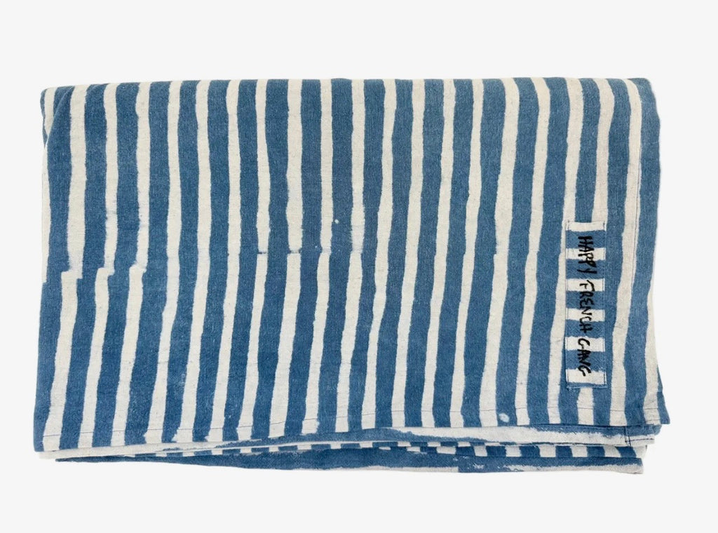 Folded blue and white striped throw with a brand label on a white background