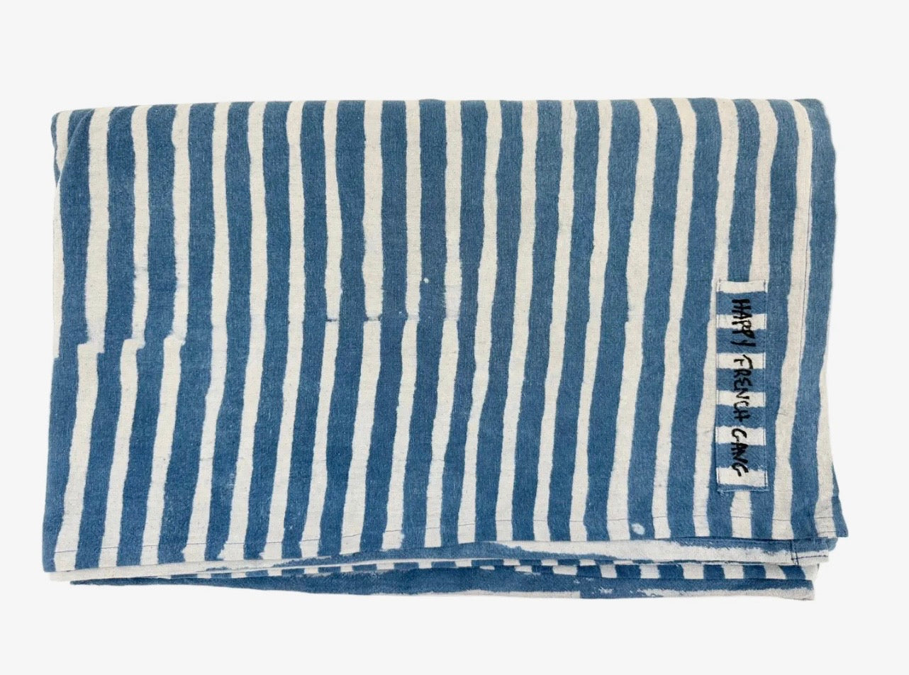 Folded blue and white striped throw with a brand label on a white background