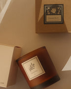 Amber candle and incense box with Jack's Daughters branding on a beige surface.