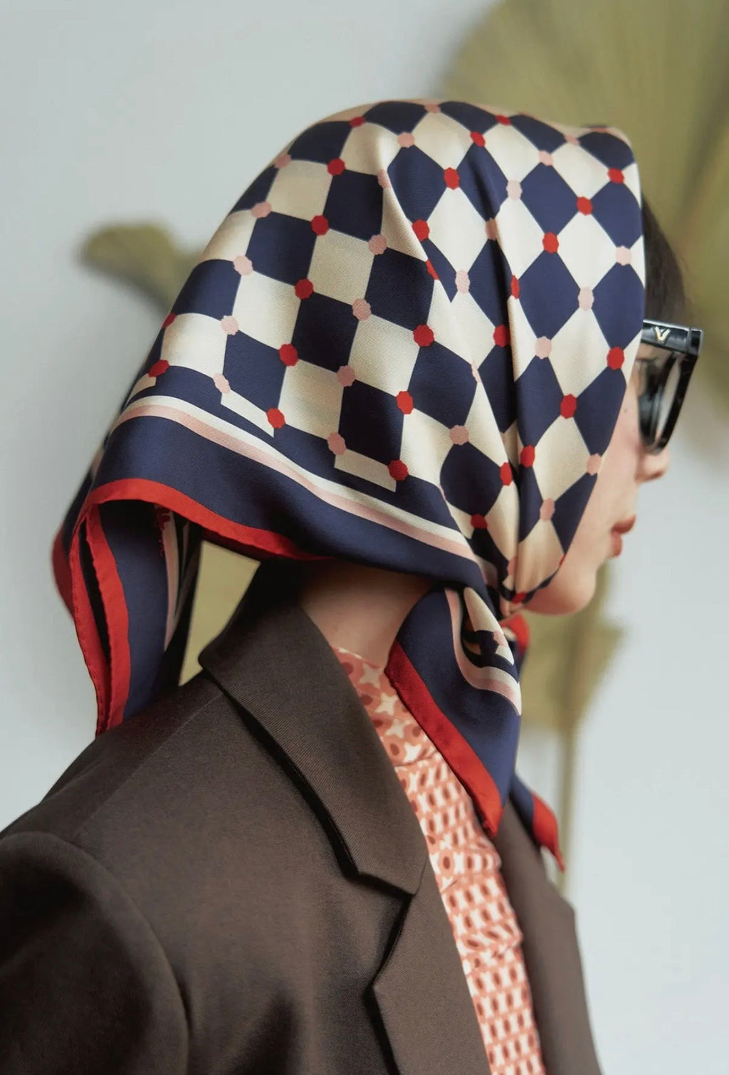 A model wearing a blue and white checkered scarf with a blurred background