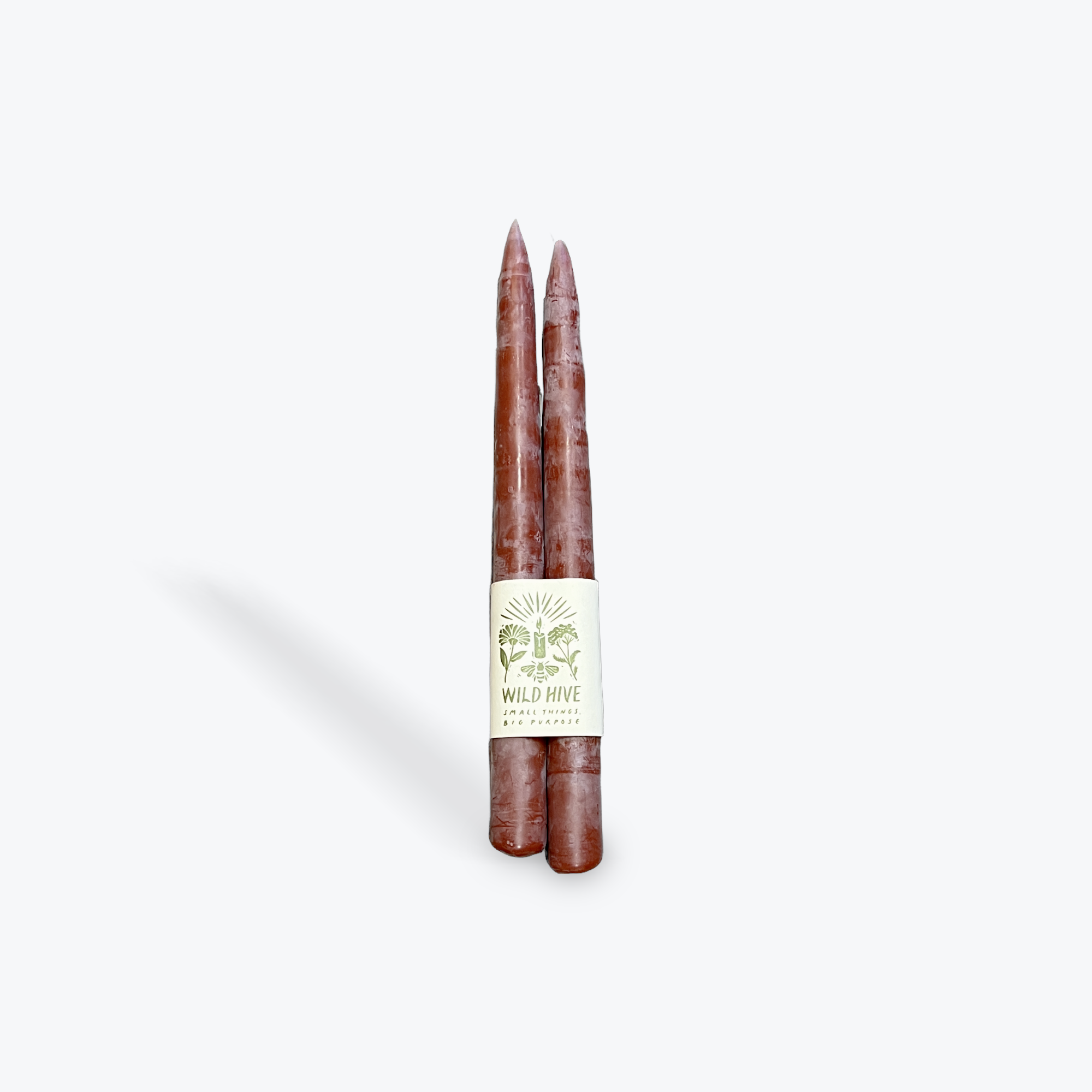 A pair of cranberry taper candles on a white background. 