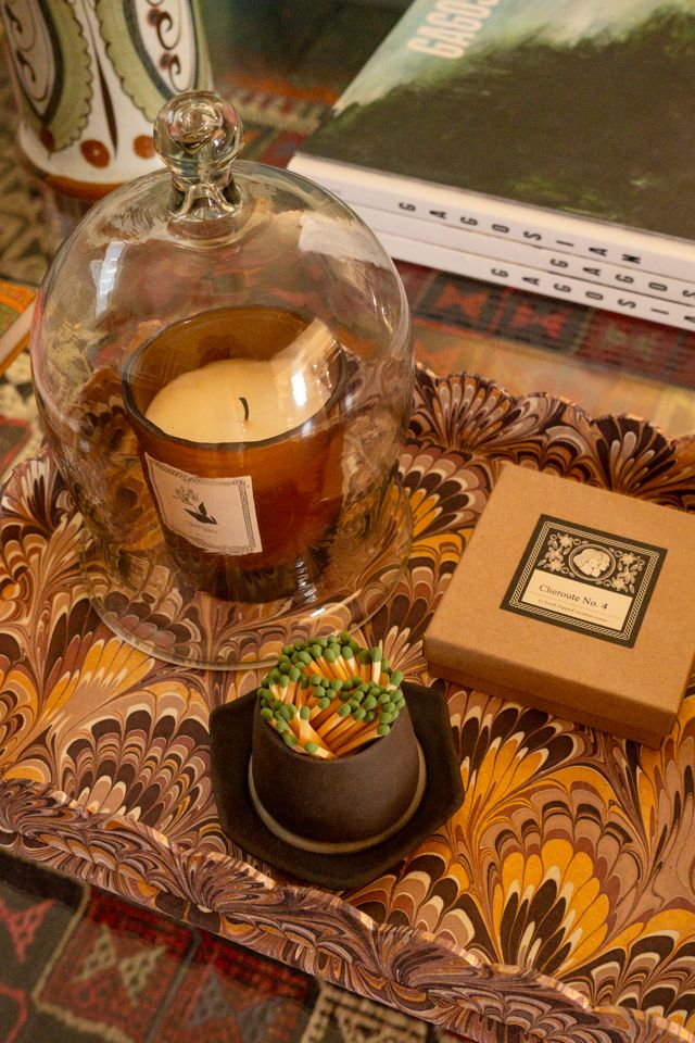 Candle in a glass cloche on a decorative marbled tray with a box and match strike.
