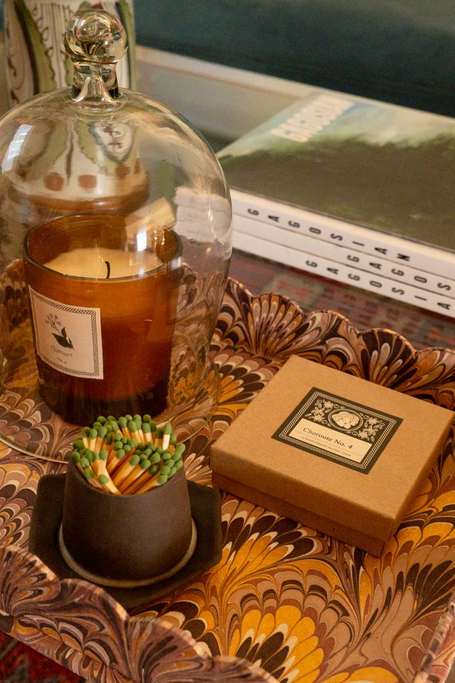 Candle with matches on a decorative marbled try, next to an incense box and a glass cloche.