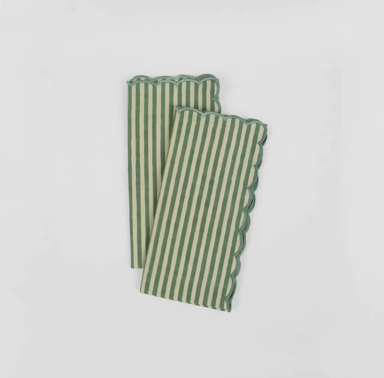 Pair of green and white stripe napkins with scalloped edge on a white background.