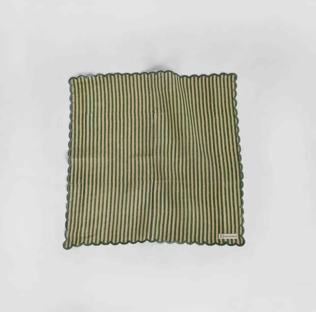 A green and white stripe napkin with scalloped edge on a white background.