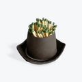 Black ceramic match holder with green matches on a white background