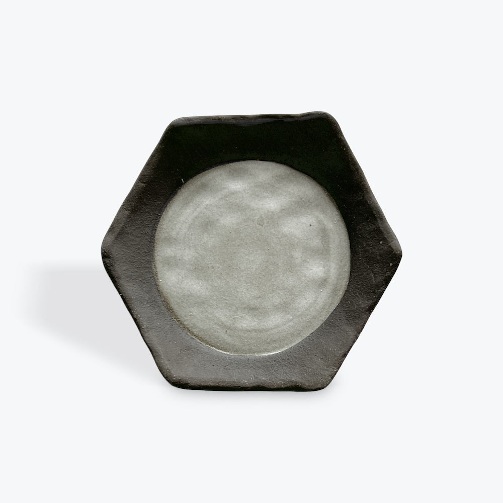 Hexagonal ceramic dish with a gray glazed circcle  inset on a white background